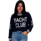 a woman wearing a navy blue "YACHT CLUB" sweater on white background
