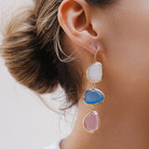 Close-up of an ear wearing a colorful earring with a neutral background