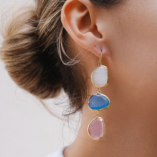Close-up of an ear wearing a colorful earring with a neutral background