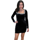 Woman wearing a black dress with floral embellishments on a white background