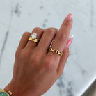 Hand wearing a gold watch and rings on a marble surface
