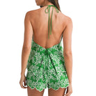 Green and white floral halter top on a model against a white background