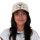A woman wearing a beige baseball cap with brown embroidery that reads 'Espresso Martini Social Club' and a white t-shirt, photographed against a solid white background.