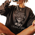 Person wearing a brown sweatshirt with 'Espresso Martini Social Club' design.
