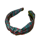 A twisted fabric headband featuring a green, red, and white tartan plaid pattern, shown against a plain white background.