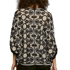 Person wearing a black and white patterned jacket on a white background