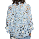 Person wearing a light blue floral crochet top on a white background