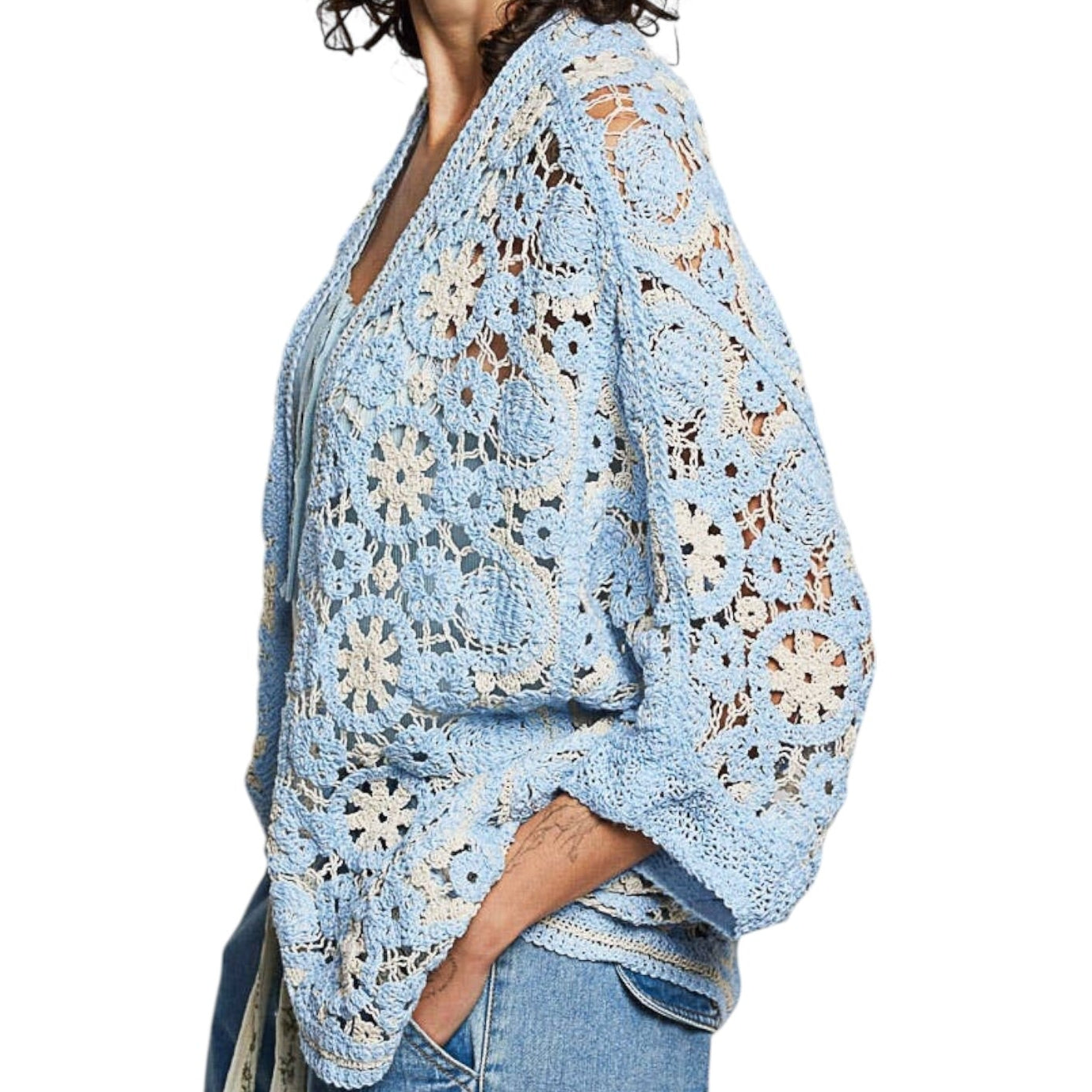 Woman wearing a light blue floral crochet shrug on a white background