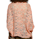 Person wearing a orange floral lace top on a white background