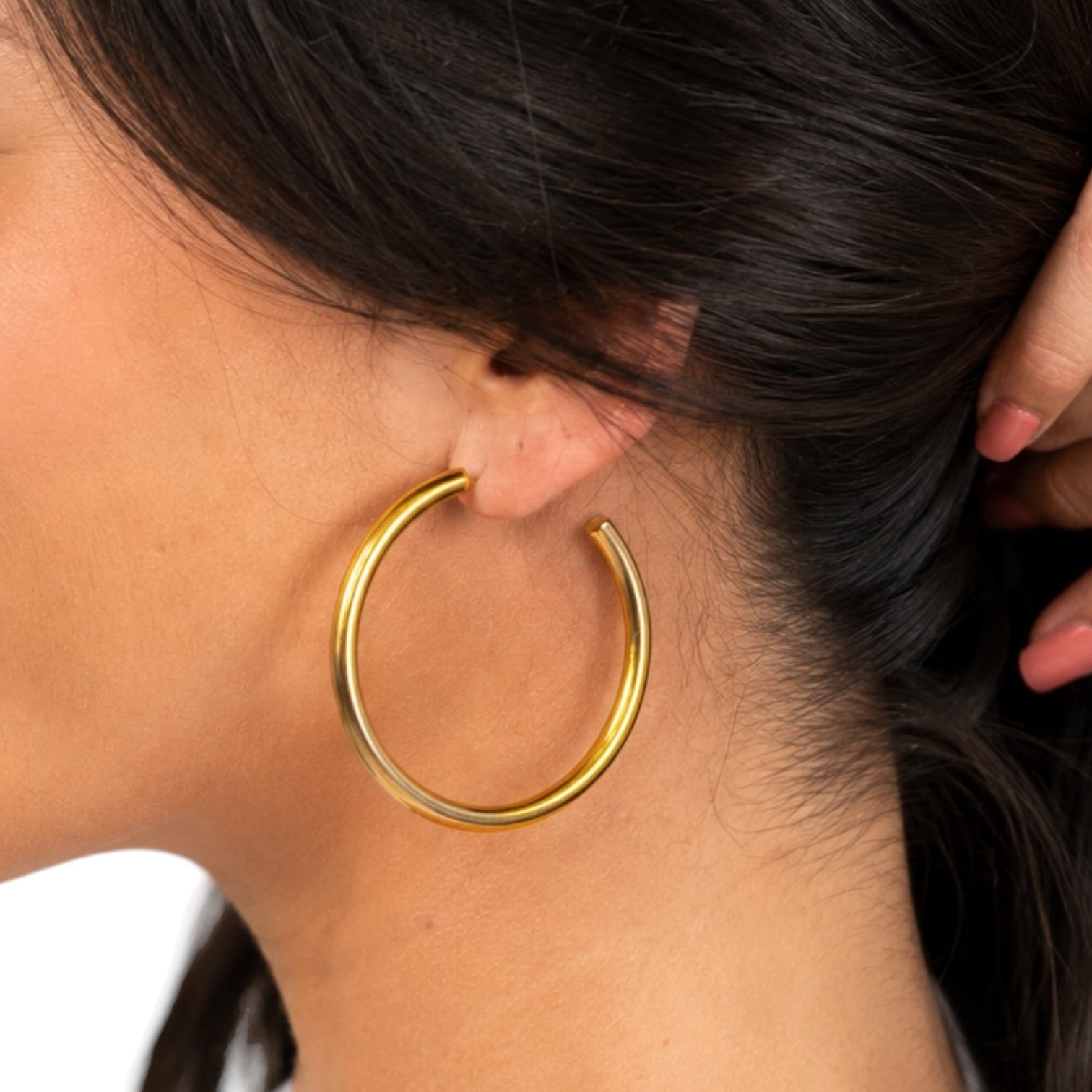 Gold hoop earring worn by a person with dark hair.
