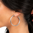 Silver hoop earring worn by a person with dark hair.