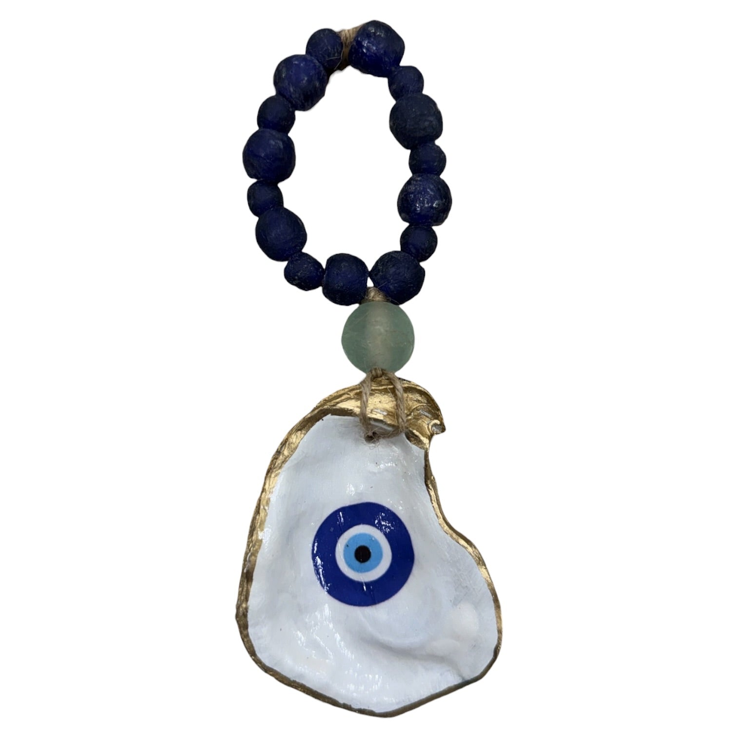 A beaded necklace with dark blue lapis lazuli-style beads, a light green stone accent, and a white oyster shell pendant featuring a blue and white evil eye design with gold-toned edges, shown on a plain white background.