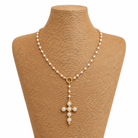 Pearl necklace with a gold cross pendant on a mannequin bust.