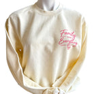 pale yellow sweatshirt with pink text 'Family Over Everything' on a white background