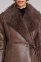 Brown leather coat with fur collar on a neutral background