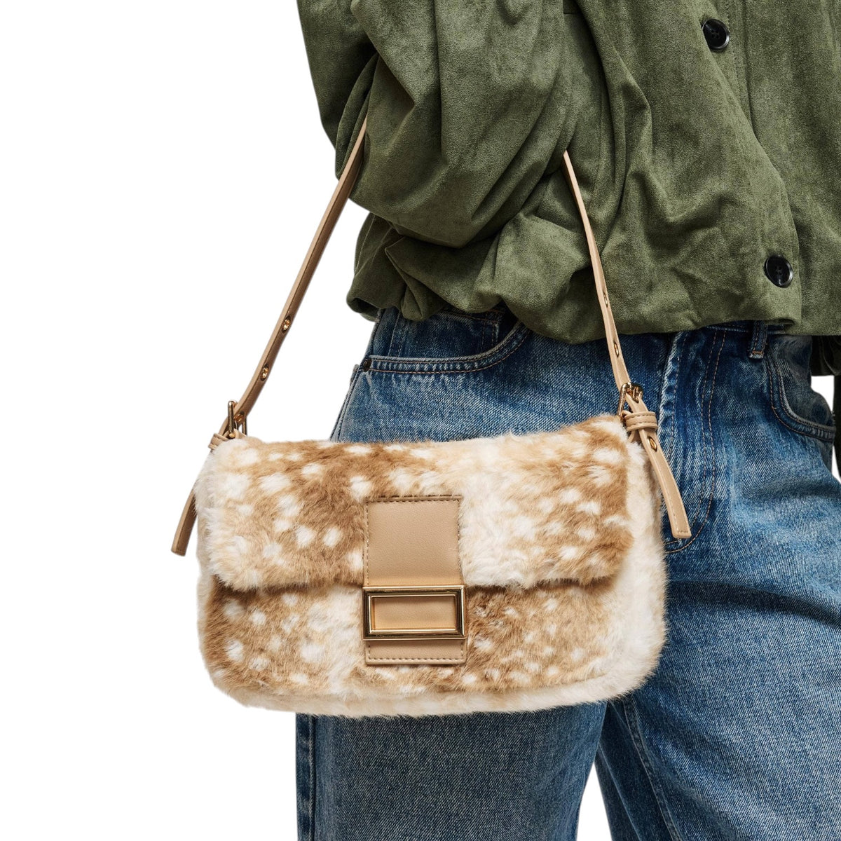 A person wearing blue jeans and an olive green shirt carries a small shoulder bag with a brown and white spotted faux-fur texture, tan leather trim, and a tan buckle closure.