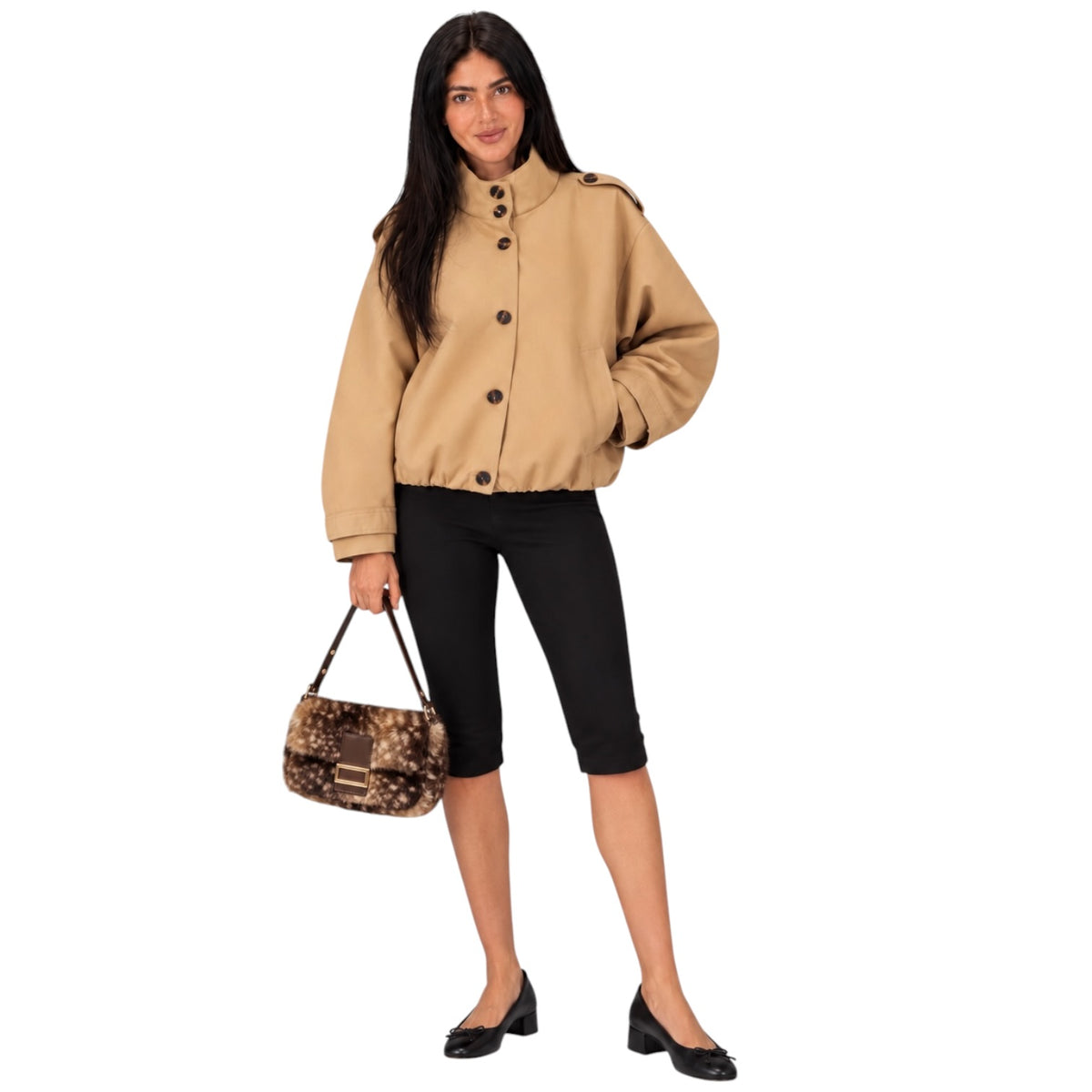 A woman modeling a cropped tan jacket with dark buttons, black capri pants, and black shoes, holding a leopard-print handbag against a plain white background.