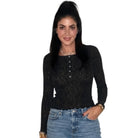 A woman modeling a black long-sleeve lace top with a buttoned henley-style neckline, paired with blue jeans, against a plain white background.