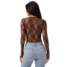 A woman shown from the back wearing a sheer brown lace long-sleeve top over light blue jeans, against a plain white background.