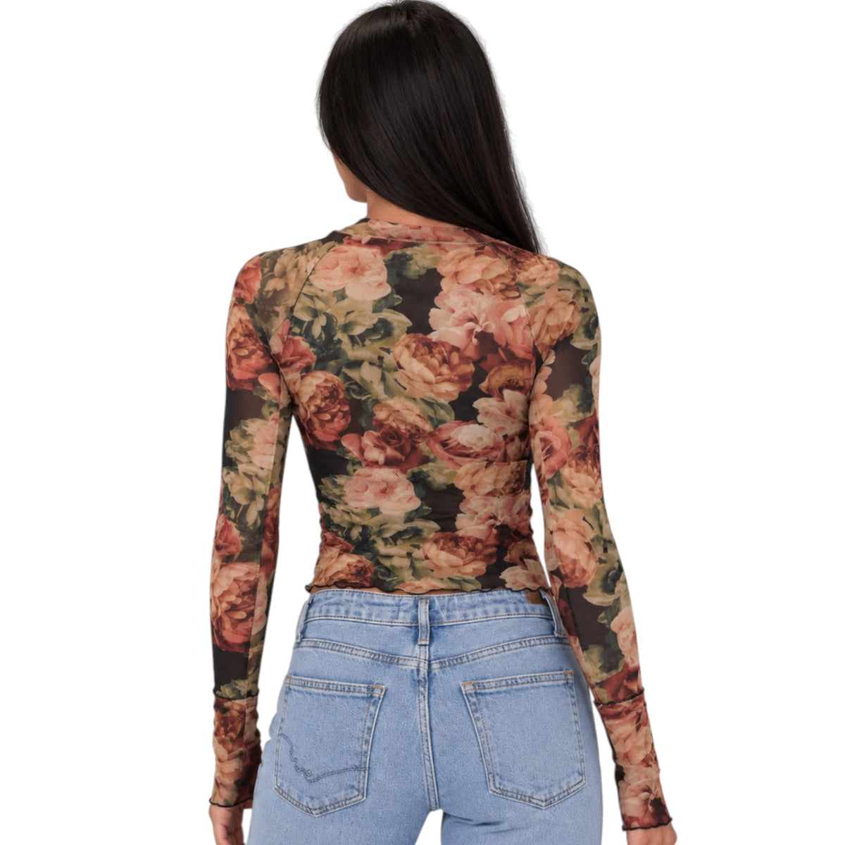 A woman viewed from the back wearing a fitted long-sleeve top with a vintage floral print in muted pink, peach, green, and brown tones, paired with light blue jeans against a plain white background.