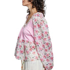 Woman wearing a floral blouse over a pink top on a white background