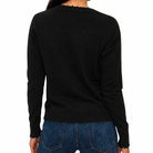 A person shown from the back wearing a black long-sleeve knit sweater with a frayed crew neckline, paired with blue jeans, against a plain white background.