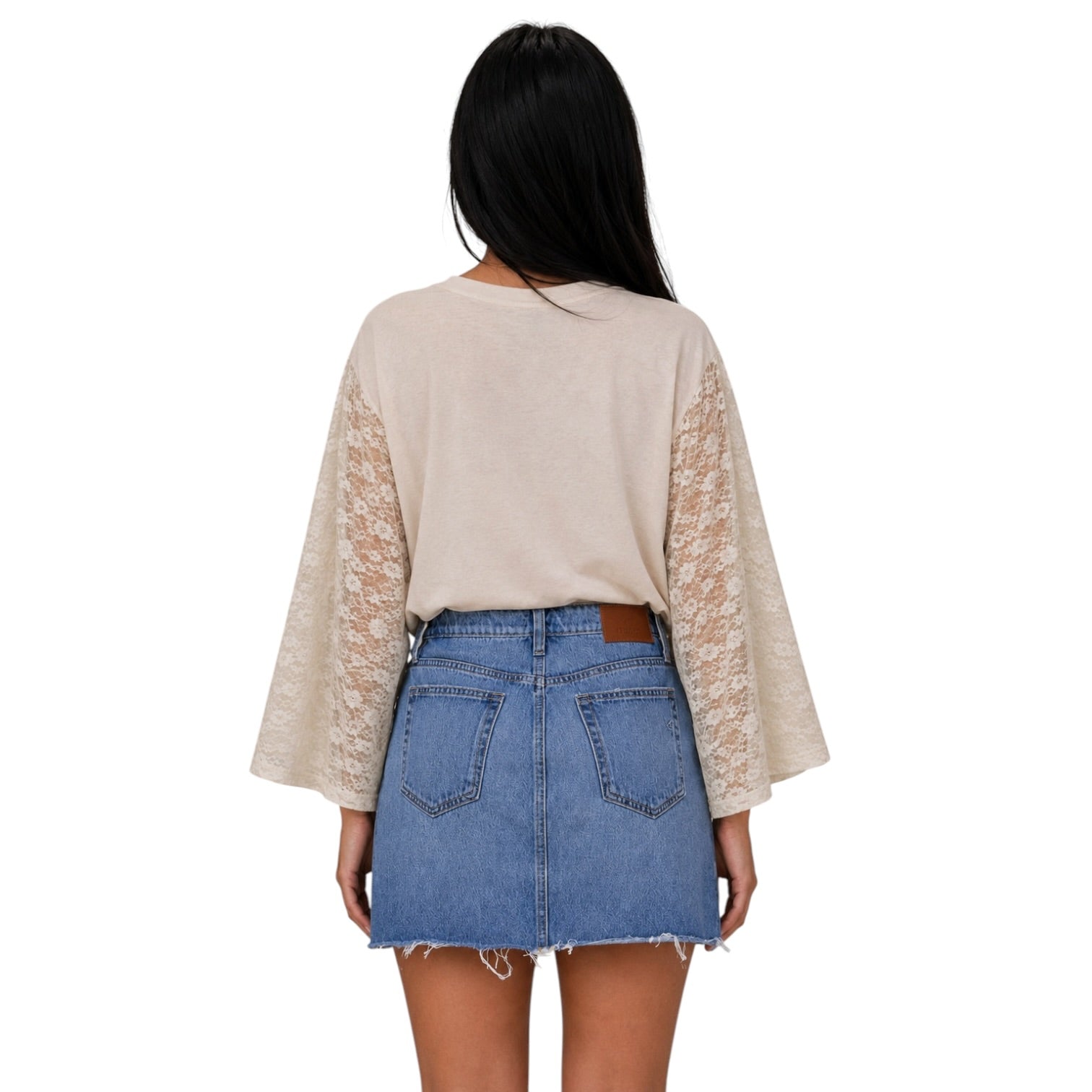 A woman shown from the back wearing a beige long-sleeve top with sheer lace sleeves and a blue denim mini skirt, against a plain white background.