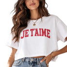 Woman wearing a white t-shirt with 'JE T'AIME' text on a plain background