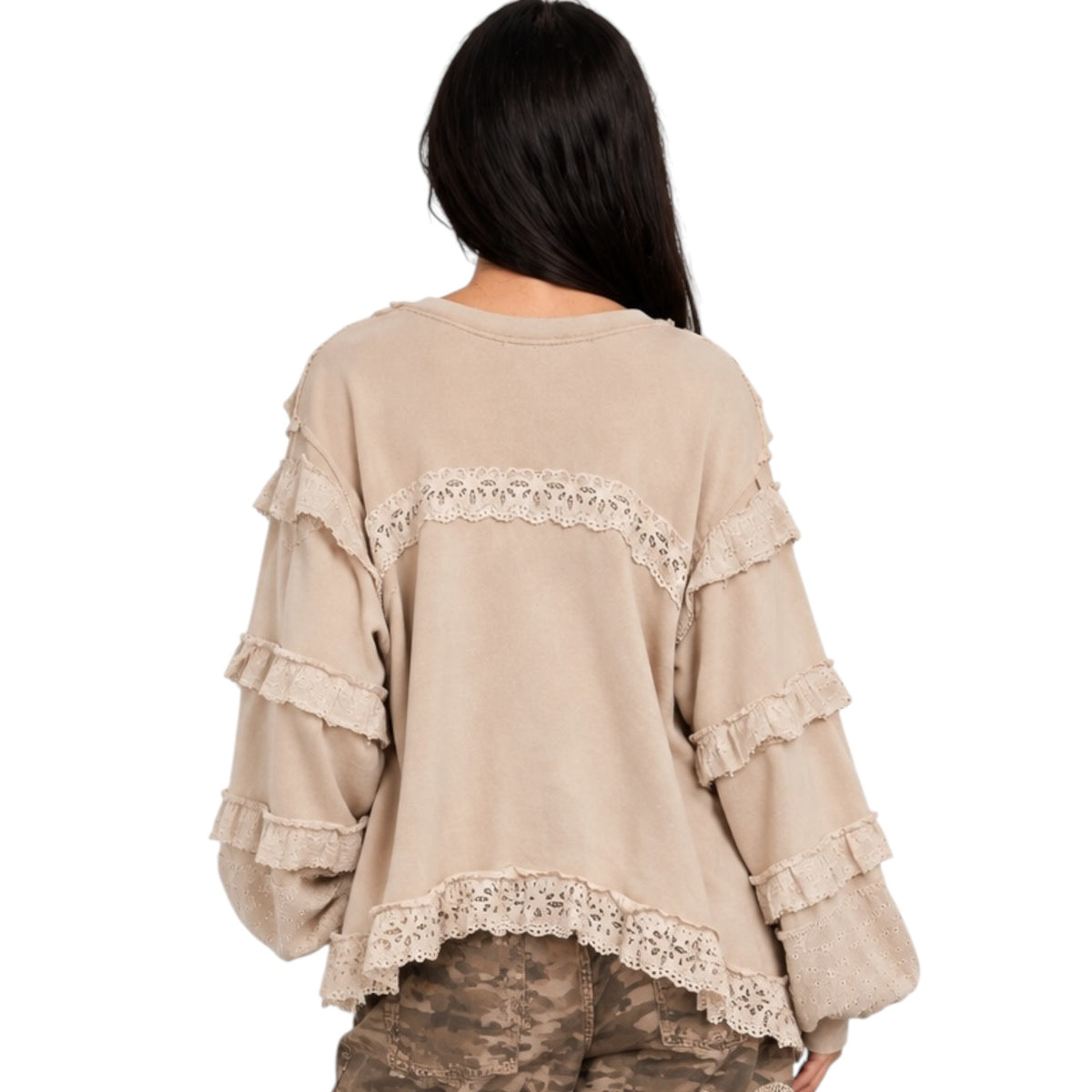 A woman viewed from the back wearing a beige long-sleeve top with layered ruffles and lace trim, paired with camouflage pants, against a plain white background.