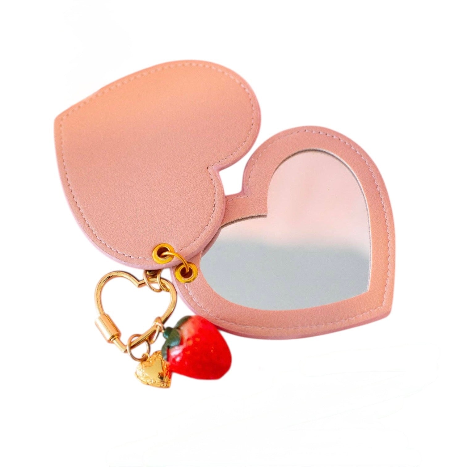 Pink heart-shaped mirror with strawberry charm on a white background