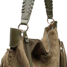 Close-up of a taupe suede shoulder bag with olive green leather straps, braided details, and gold-tone hardware on a white background.