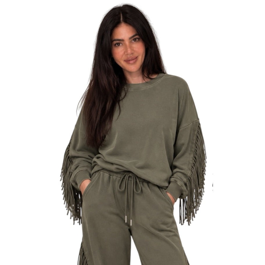 A woman modeling an olive green lounge set featuring a long-sleeve sweatshirt with fringe detailing on the sleeves and matching drawstring sweatpants, set against a plain white background.