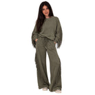 A woman modeling an olive green lounge set featuring a long-sleeve sweatshirt with fringe detailing on the sleeves and matching drawstring sweatpants, set against a plain white background.