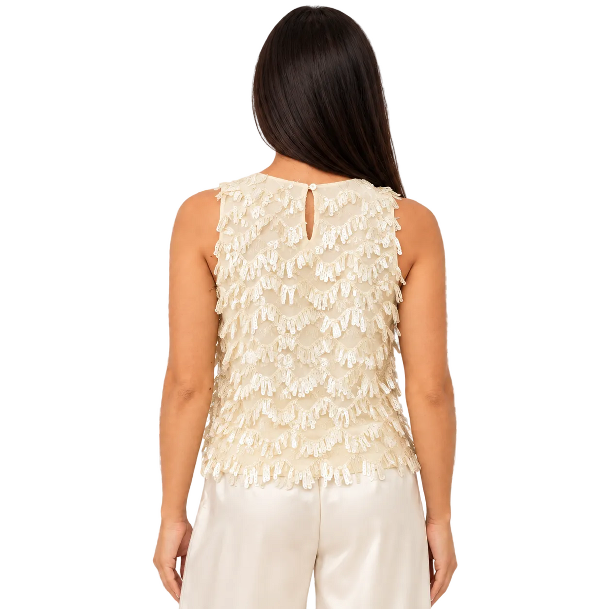 A woman shown from the back wearing a sleeveless cream top with layered ruffle detailing and a small keyhole cutout at the neckline, paired with light cream pants against a checkered transparency-style background.