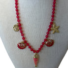 A red beaded necklace with gold-toned shell and starfish charms, displayed on a neutral fabric mannequin bust.