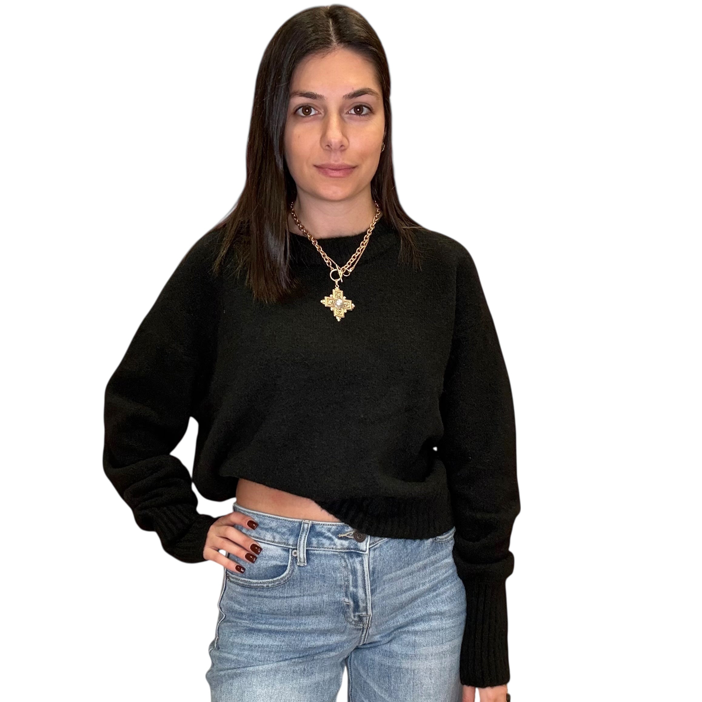 Woman wearing a black sweater and blue jeans on a white background