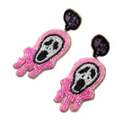A pair of handmade beaded earrings shaped like stylized pink and white skulls with black details and dark purple backing, shown on a plain white background.