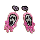 A pair of beaded dangle earrings featuring a pink and white Ghostface design with black and purple eyes, outlined in gold-tone metal on a white background.