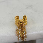 Gold ring with chains and pearls on a light gray background