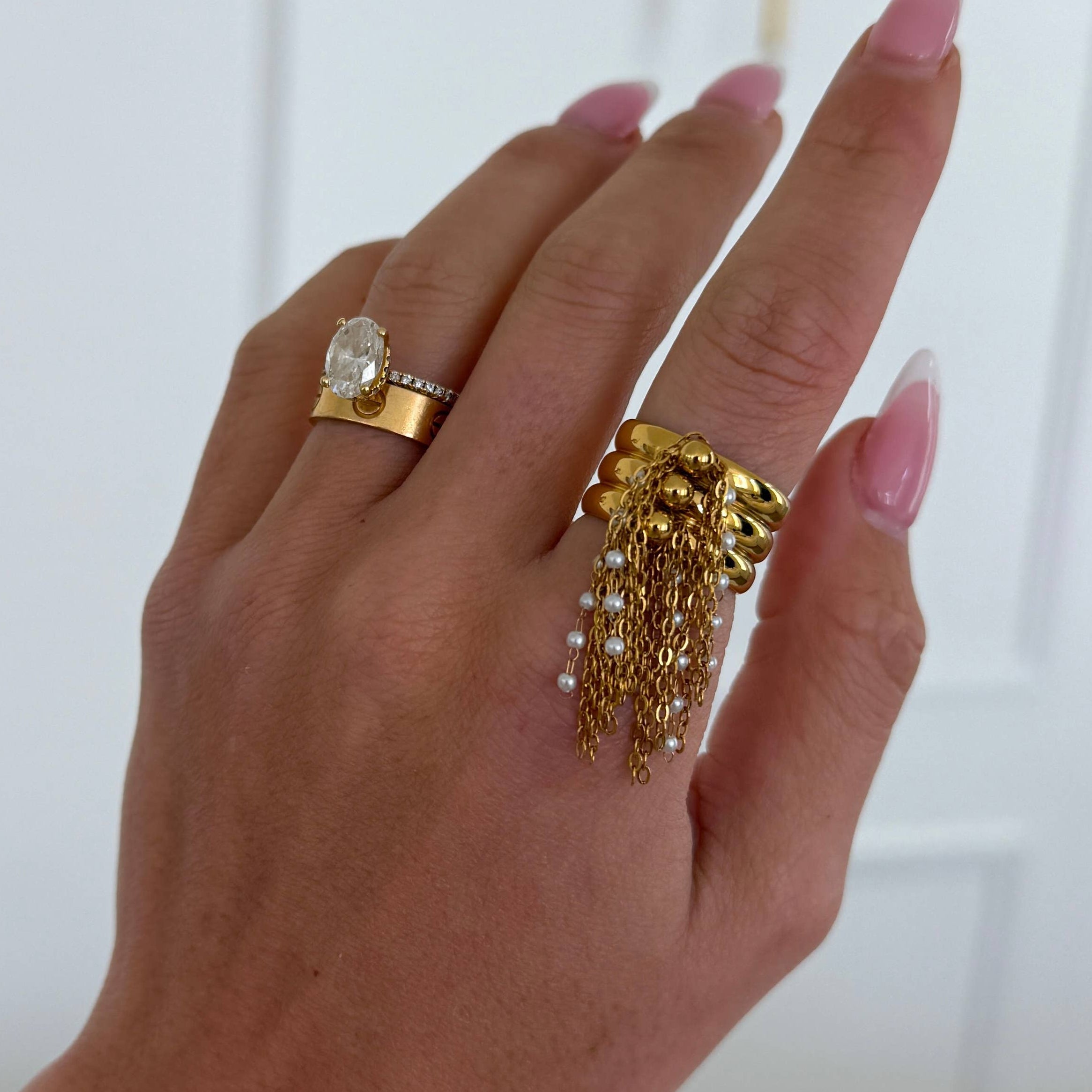 Hand wearing a gold ring with intricate designs on a white background