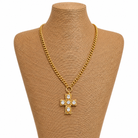 Gold chain necklace with a cross pendant on a brown mannequin bust.