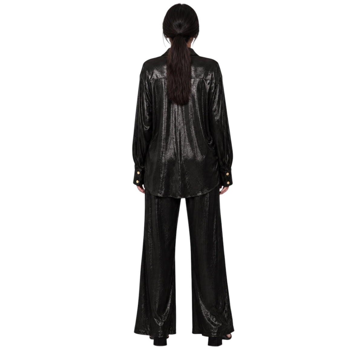 A model viewed from the back wearing a shiny black long-sleeve jacket and matching wide-leg pants against a plain white background.