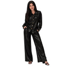 A woman modeling a shiny black two-piece lounge set consisting of a long-sleeve button-front top and matching wide-leg pants, photographed against a plain white background.