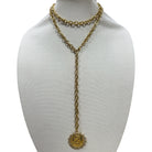 Gold chain necklace with a pendant on a mannequin bust against a white background