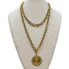 Gold chain necklace with a pendant on a mannequin bust.