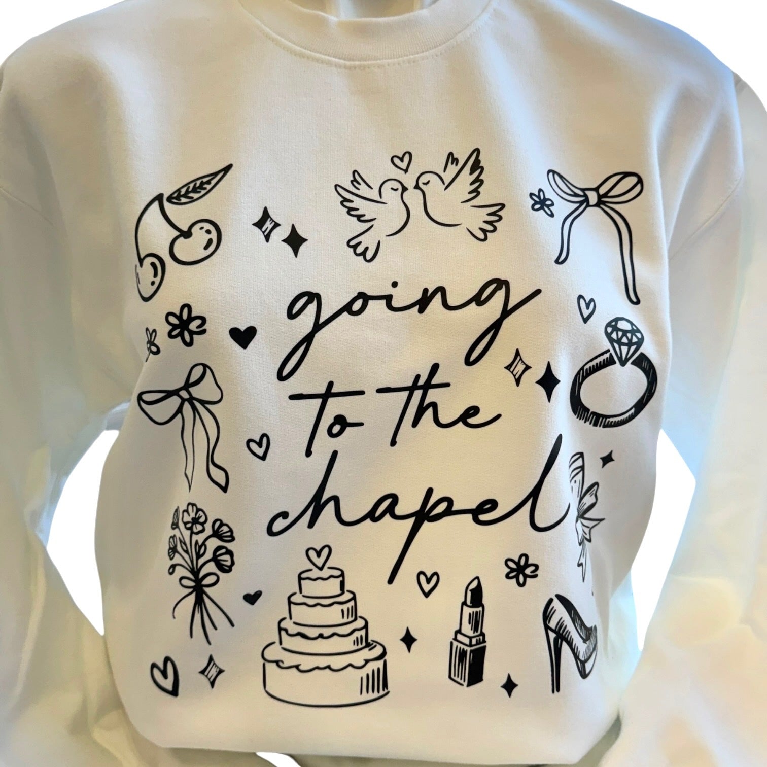 White sweatshirt with black graphic designs and text 'going to the chapel' on a white background