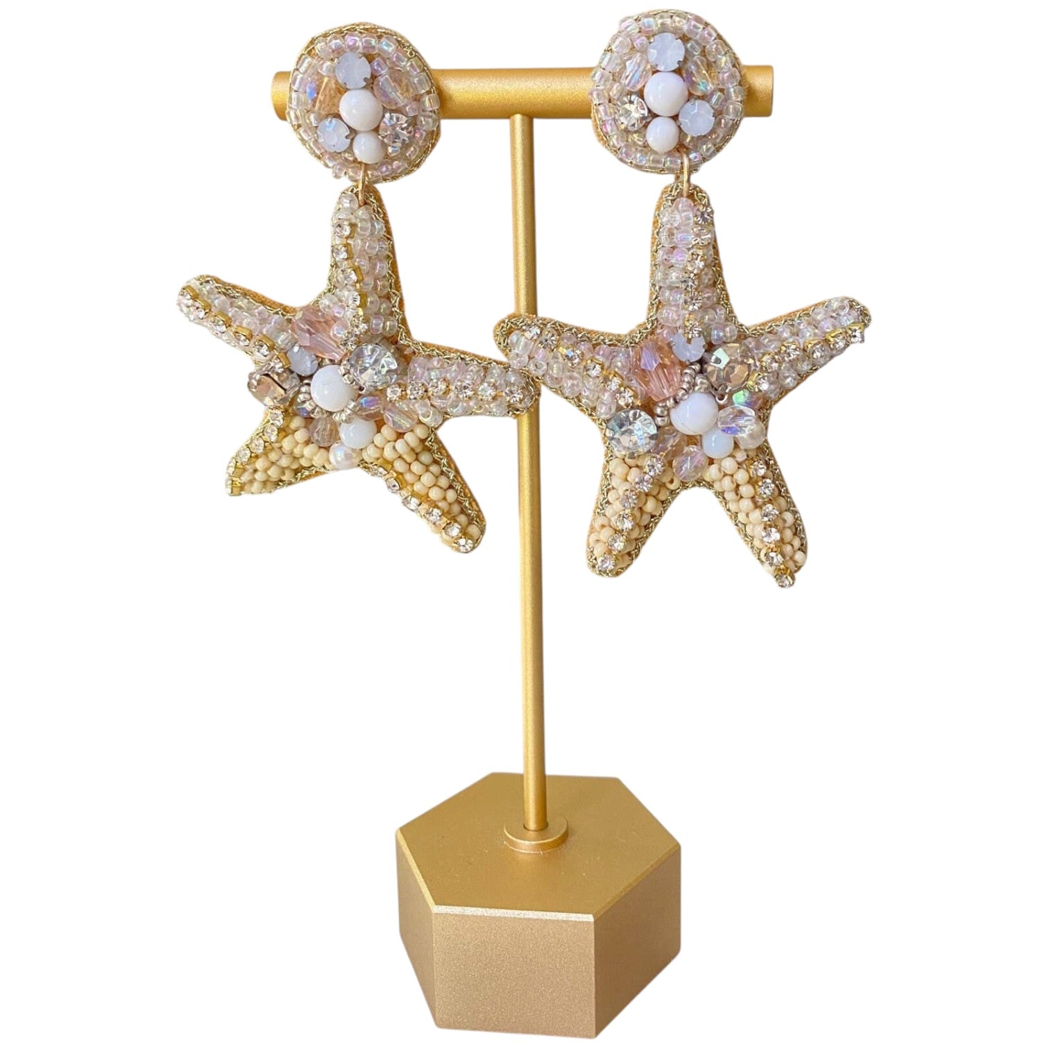 Starfish-shaped earrings on a gold stand with a white background
