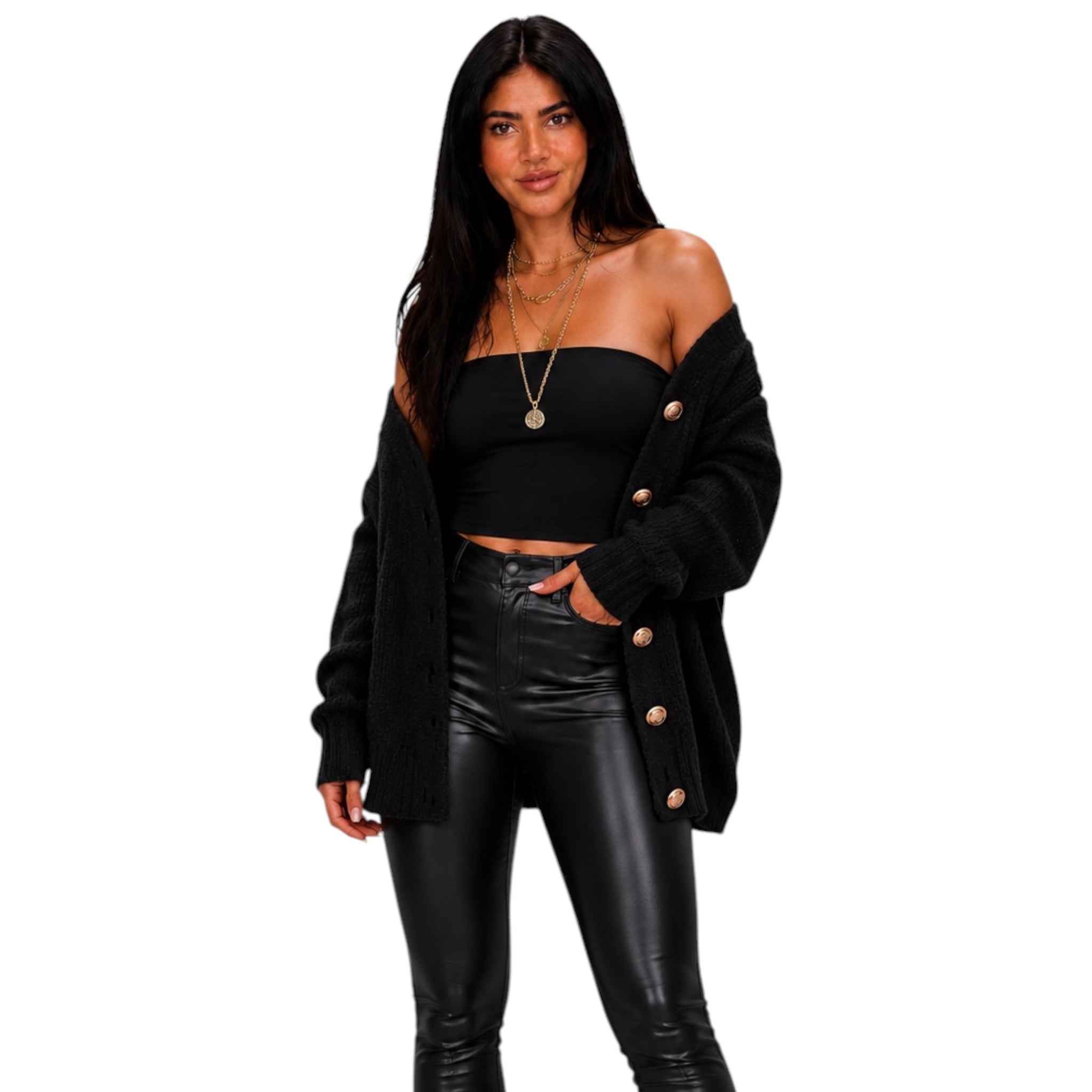 A woman modeling a black off-the-shoulder knit cardigan with gold buttons, a black strapless crop top, and black faux-leather pants against a plain white background.