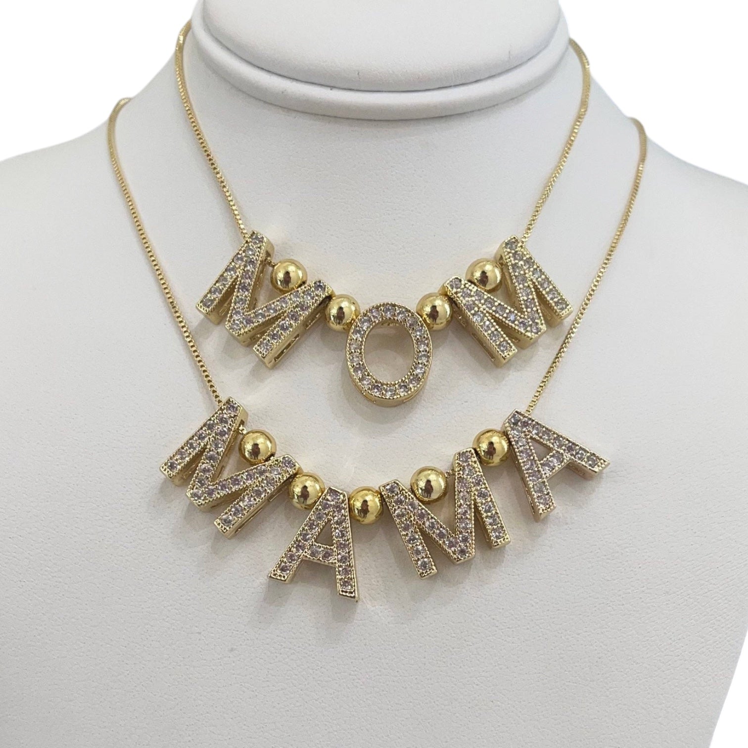 Gold necklace with 'MOM' and 'MAMA' letters on a mannequin.