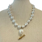 Pearl necklace with a gold fish pendant on a mannequin bust.